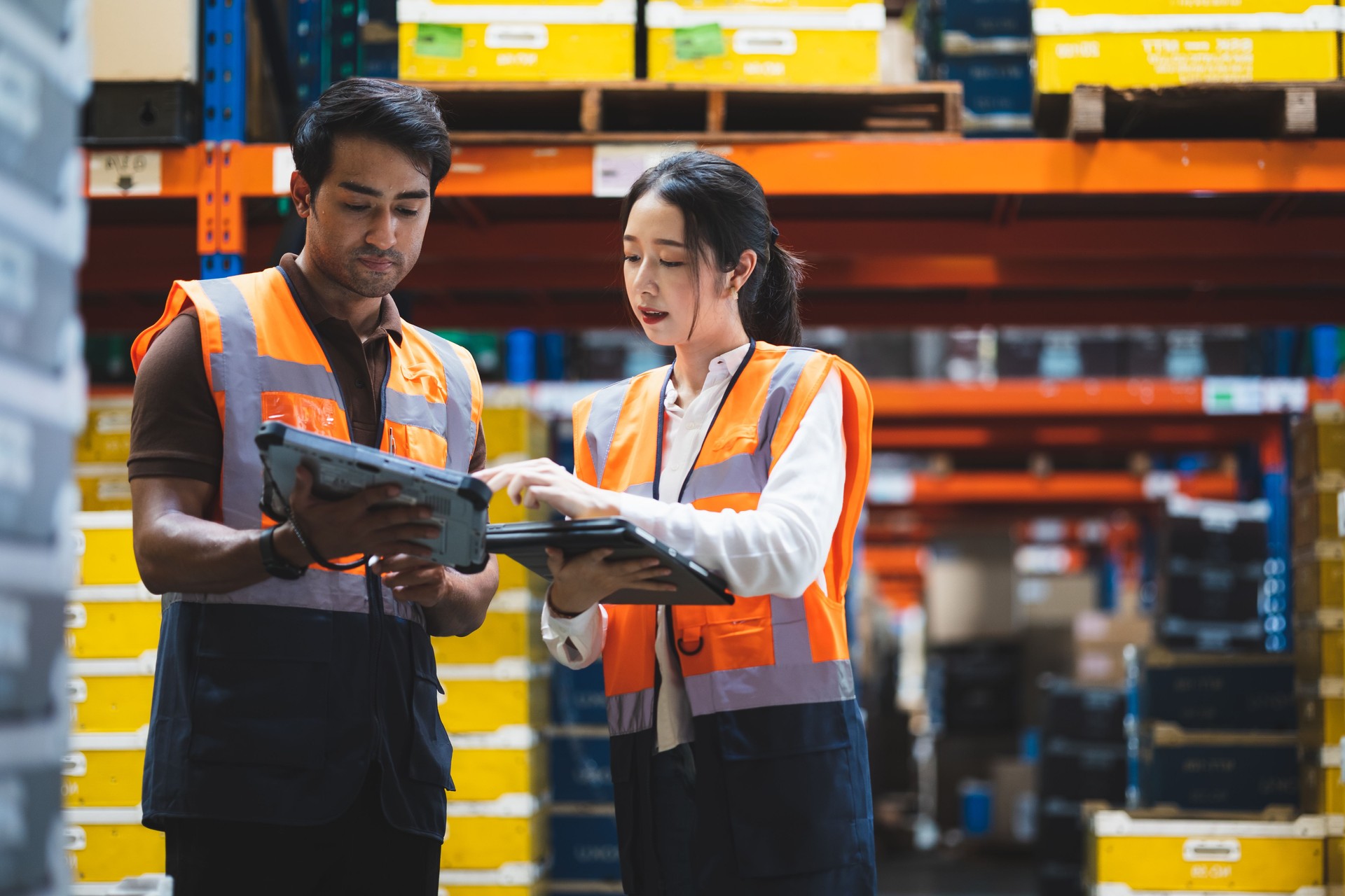 Warehouse worker and manager checks stock and inventory with using digital tablet computer in the retail warehouse full of shelves with goods. Working in logistics, Distribution center.