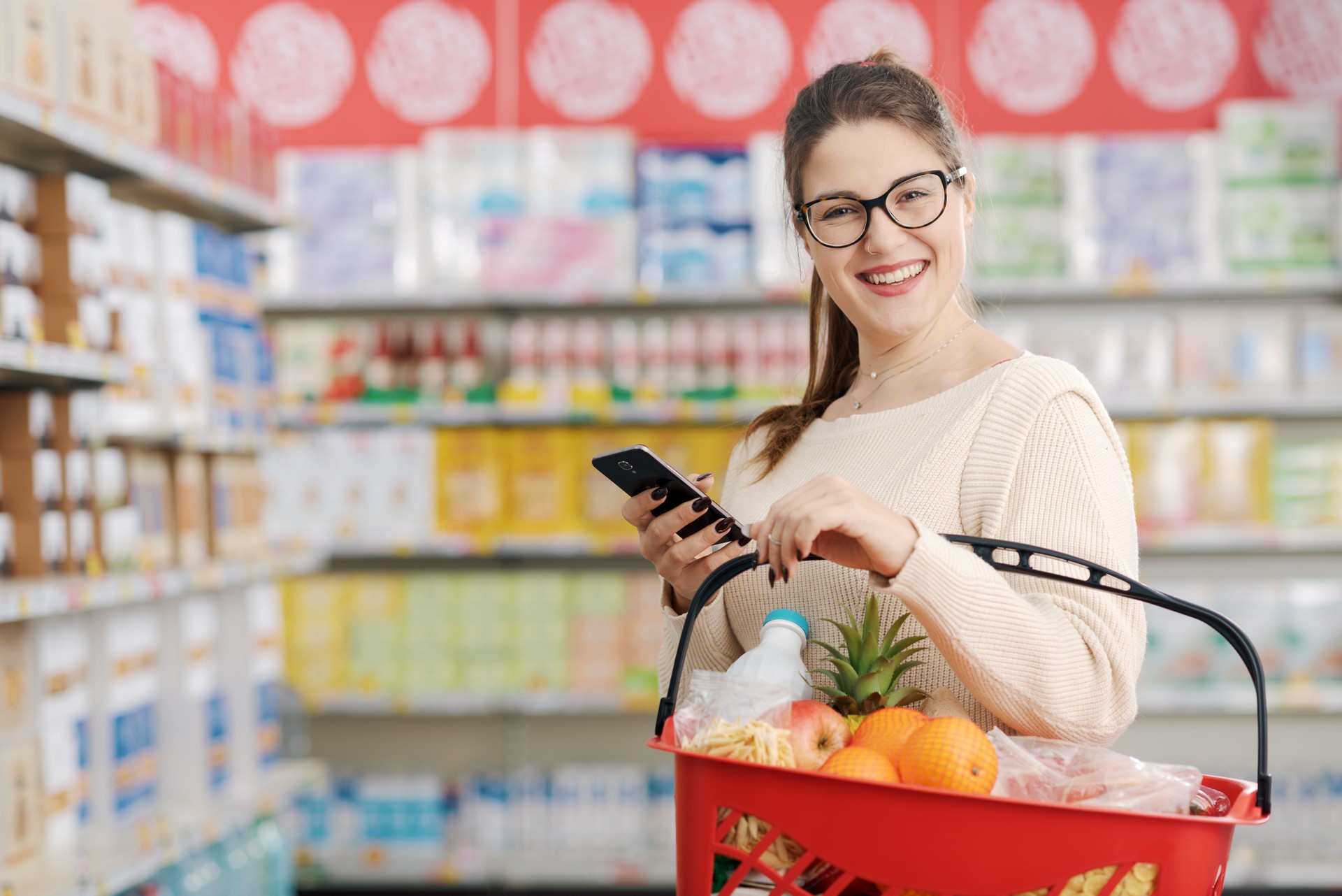 Smiling woman using apps on her smartphone at the grocery store
